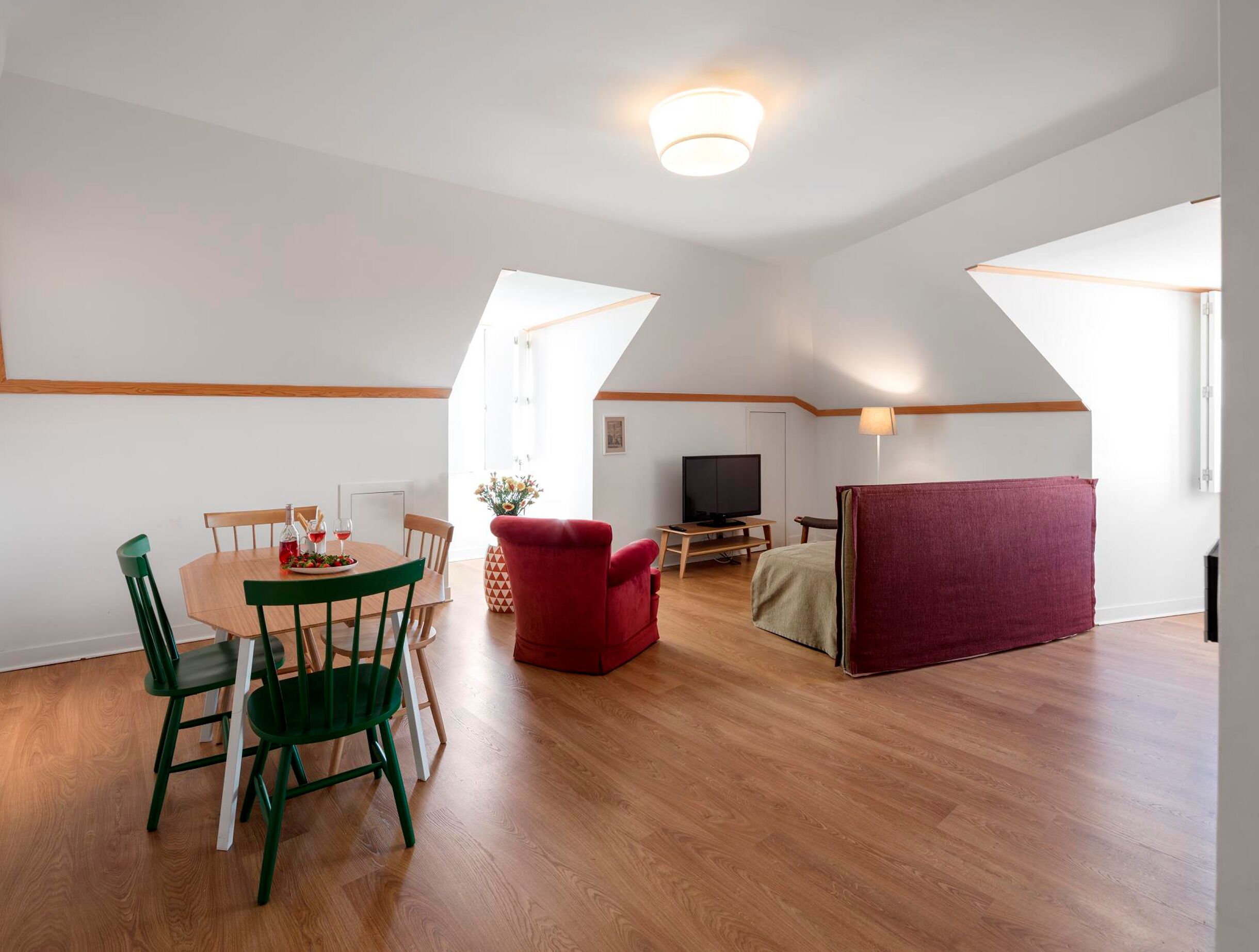 Un loft spacieux comprenant un coin repas, un téléviseur et un canapé rouge.