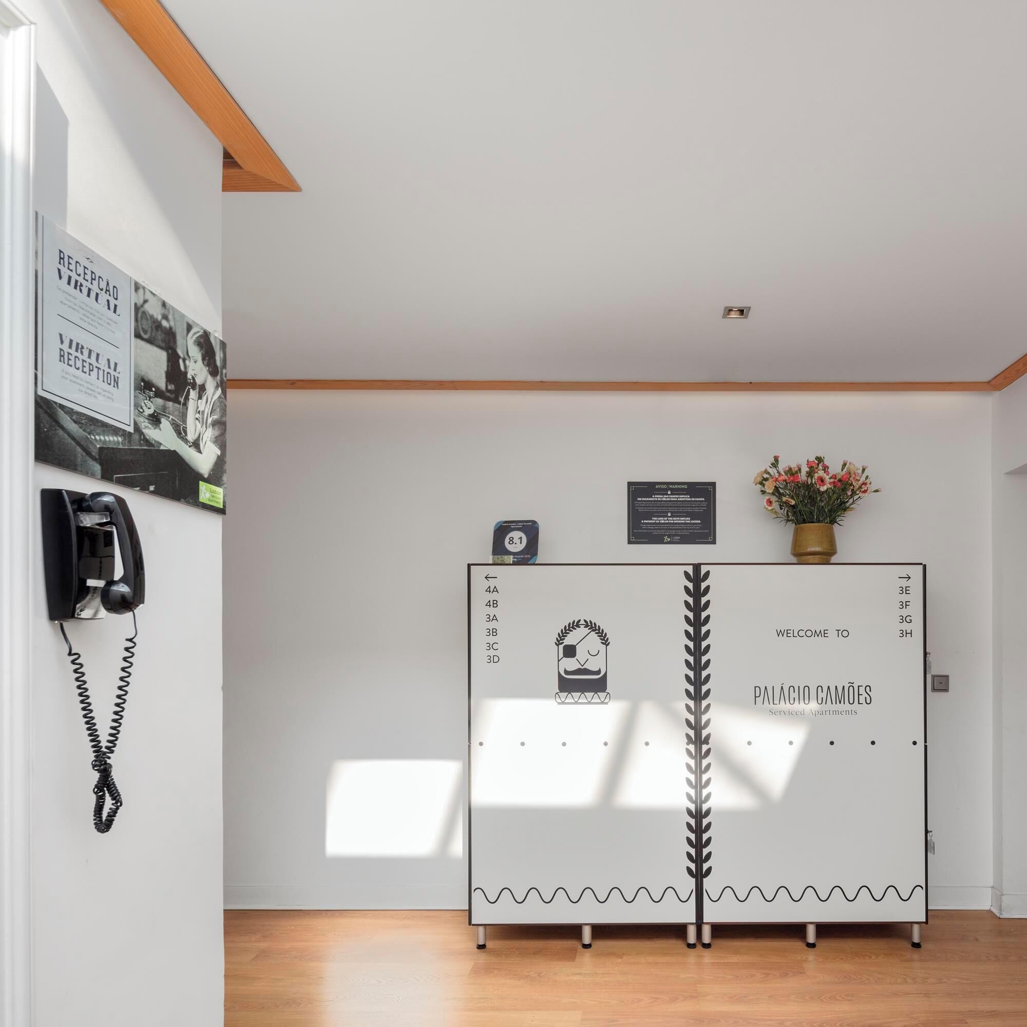 A reception desk with a sign indicating 'Welcome to Pálácio Camões Service Apartments.'