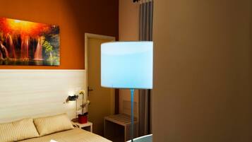 A hotel room with a bed, a nightstand, a lamp, and a painting on the wall.
