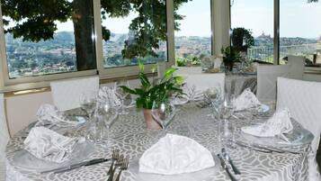A dining table set for six with a view of a cityscape through large windows.