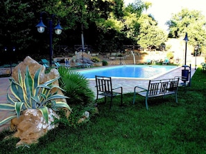 Una piscina al aire libre, sillones reclinables de piscina