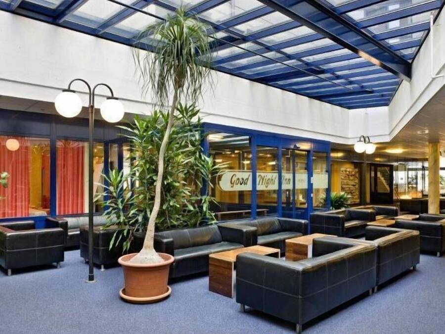 A spacious lobby with a high ceiling, large seating area, and a central potted plant.