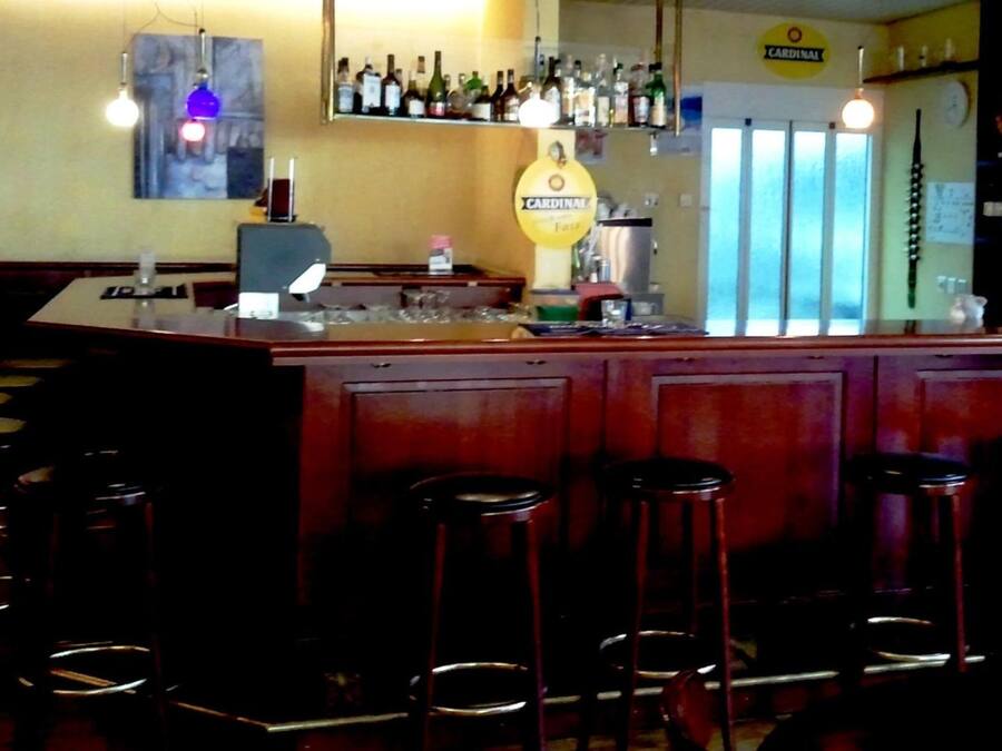 A bar area with a counter, stools, and a variety of bottles on shelves.