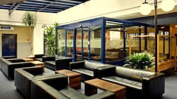 Un vestíbulo de hotel con asientos de cuero, un mostrador de recepción y un área con paredes de vidrio.