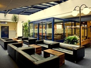 A hotel lobby with leather seating, a reception desk, and a glass-enclosed area.
