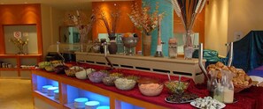 Buffet com diversos alimentos e uma seleção de bebidas.