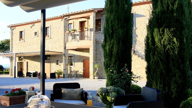 Un bâtiment en pierre doté d’un balcon, de sièges en plein air et de plantes en pot.