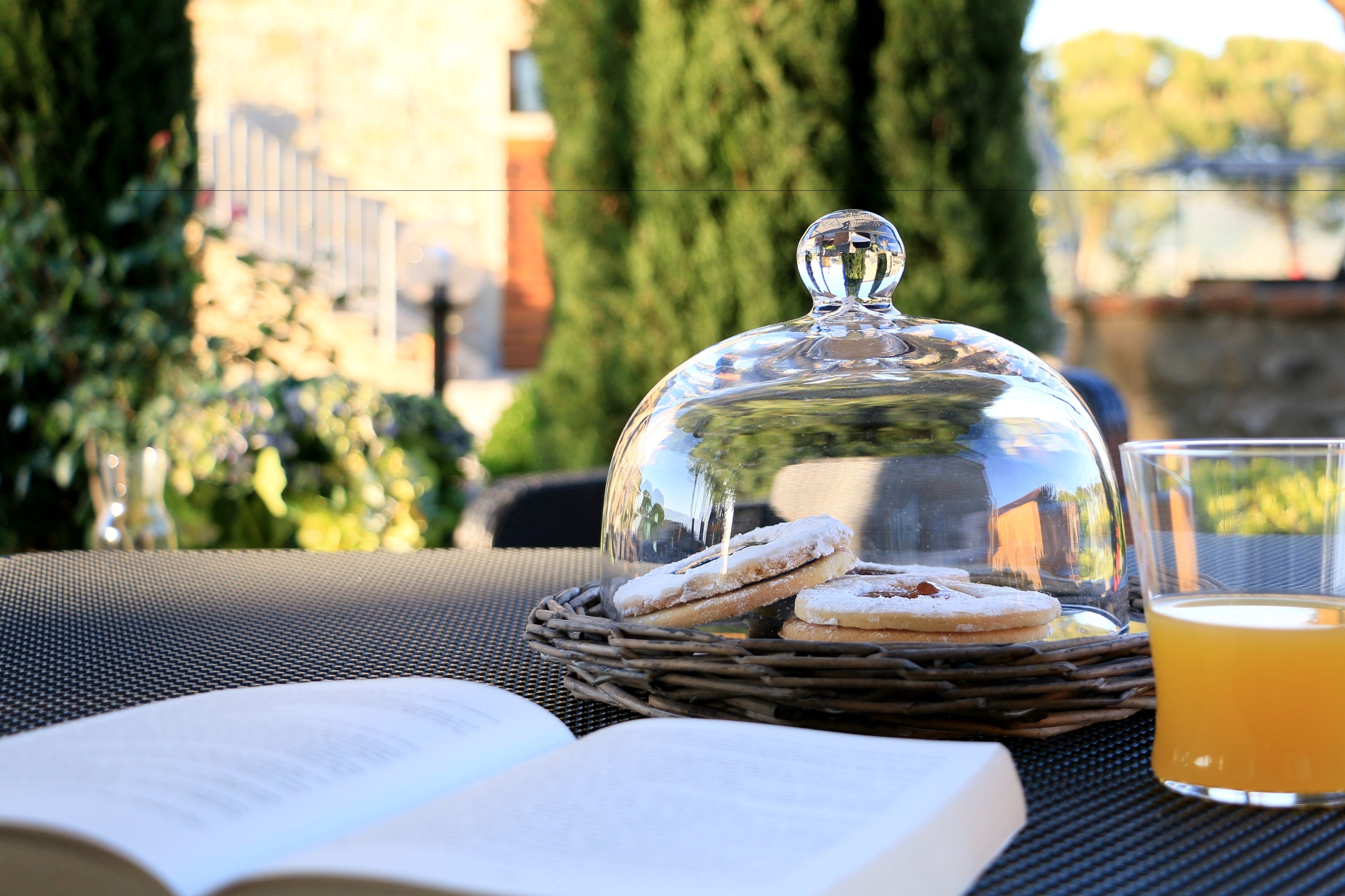 A wicker basket with pastries and a glass of orange juice on a table with an open book.