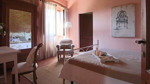 Une chambre à coucher avec un lit, une chaise, un bureau et une fenêtre avec des rideaux.
