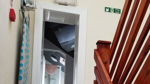 A staircase with a striped carpet, a wooden handrail, and a fire exit sign. - Trentham Private Hotel (Blackpool)