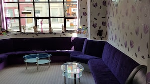 A living room with a purple sofa, a glass coffee table, and a patterned wall. - Trentham Private Hotel (Blackpool)