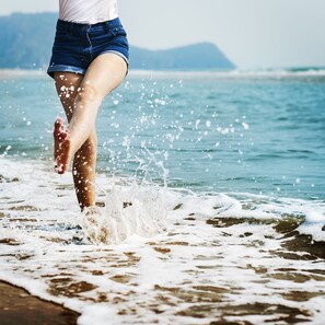 A person walking on a beach with waves crashing onto the shore. - Hostal Moscatel (Málaga)