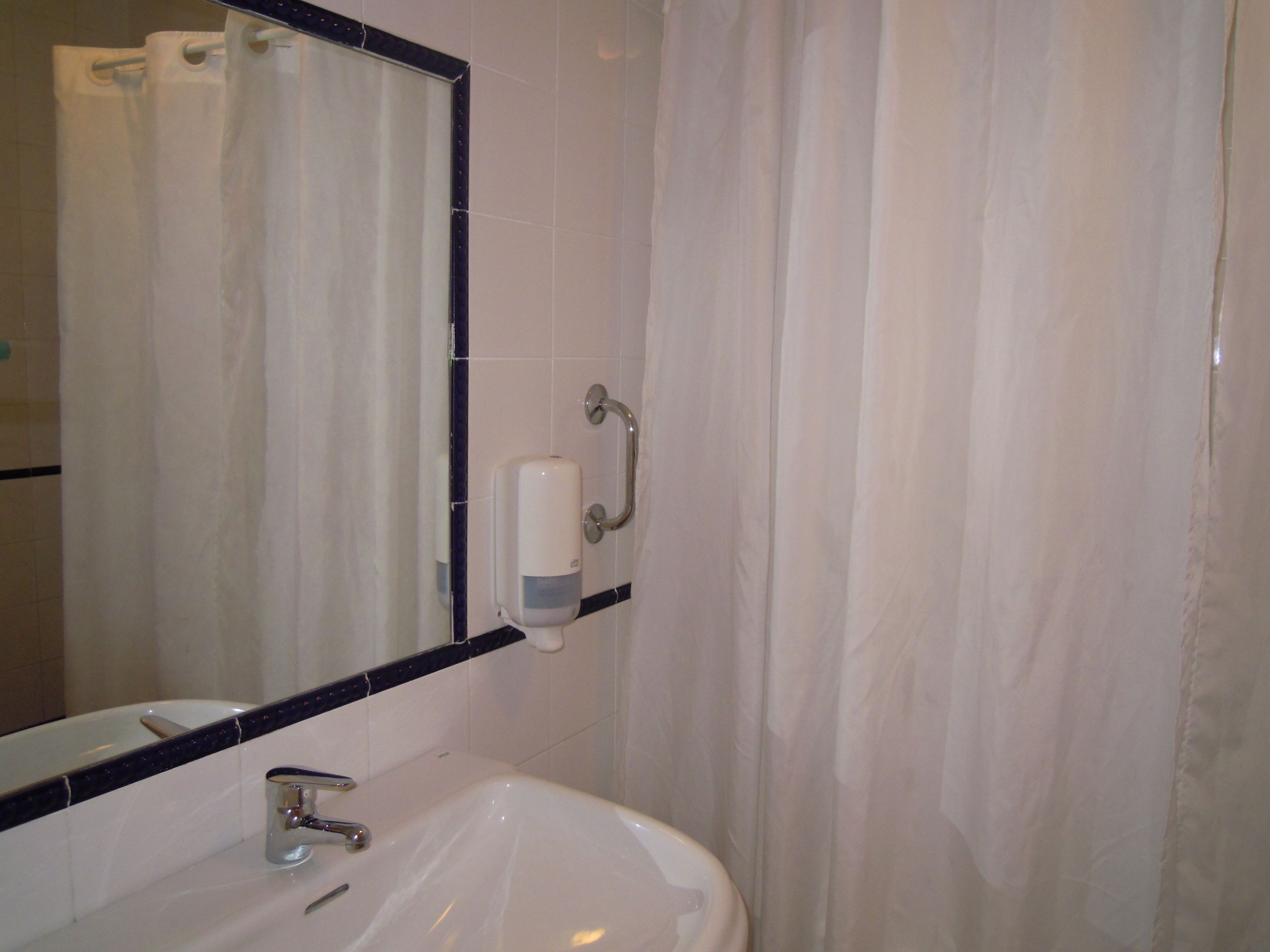 A bathroom with a white sink, a mirror, and a shower curtain.