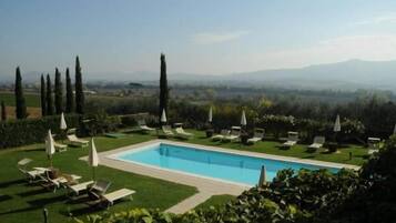 Alberca al aire libre, sombrillas en la alberca y camastros