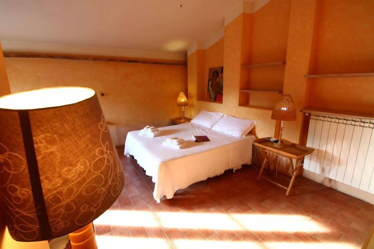 Een slaapkamer met een bed, bedlampjes en een radiator.