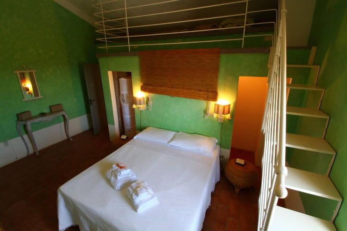 Een hotelkamer met een bed, twee nachtkastjes, een spiegel en een trap.