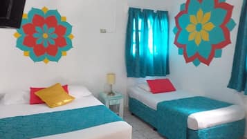 A hotel room with two beds, each with a blue and white bedspread, a red and yellow pillow, and a wall decoration.