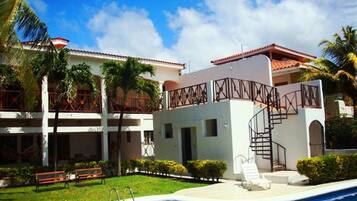 Un hotel con piscina, palmeras y techo de tejas rojas.