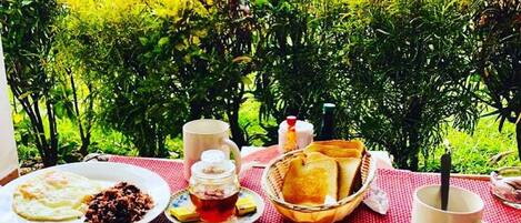 A table set outdoors with breakfast items including toast, eggs, and a beverage.