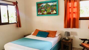 A bedroom with a bed, a nightstand, a chair, a painting, and curtains.