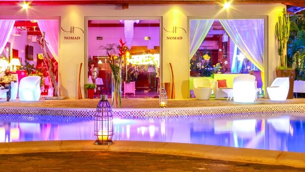 A hotel lobby with a pool, seating areas, and a reception desk. - Nomad Suites Residence (Libreville)