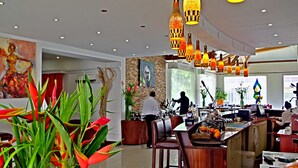 A modern hotel lobby with a bar area, seating, and decorative plants. - Nomad Suites Residence (Libreville)