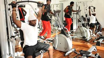 A gym with various exercise machines, including treadmills and elliptical trainers, and mirrors on the walls.