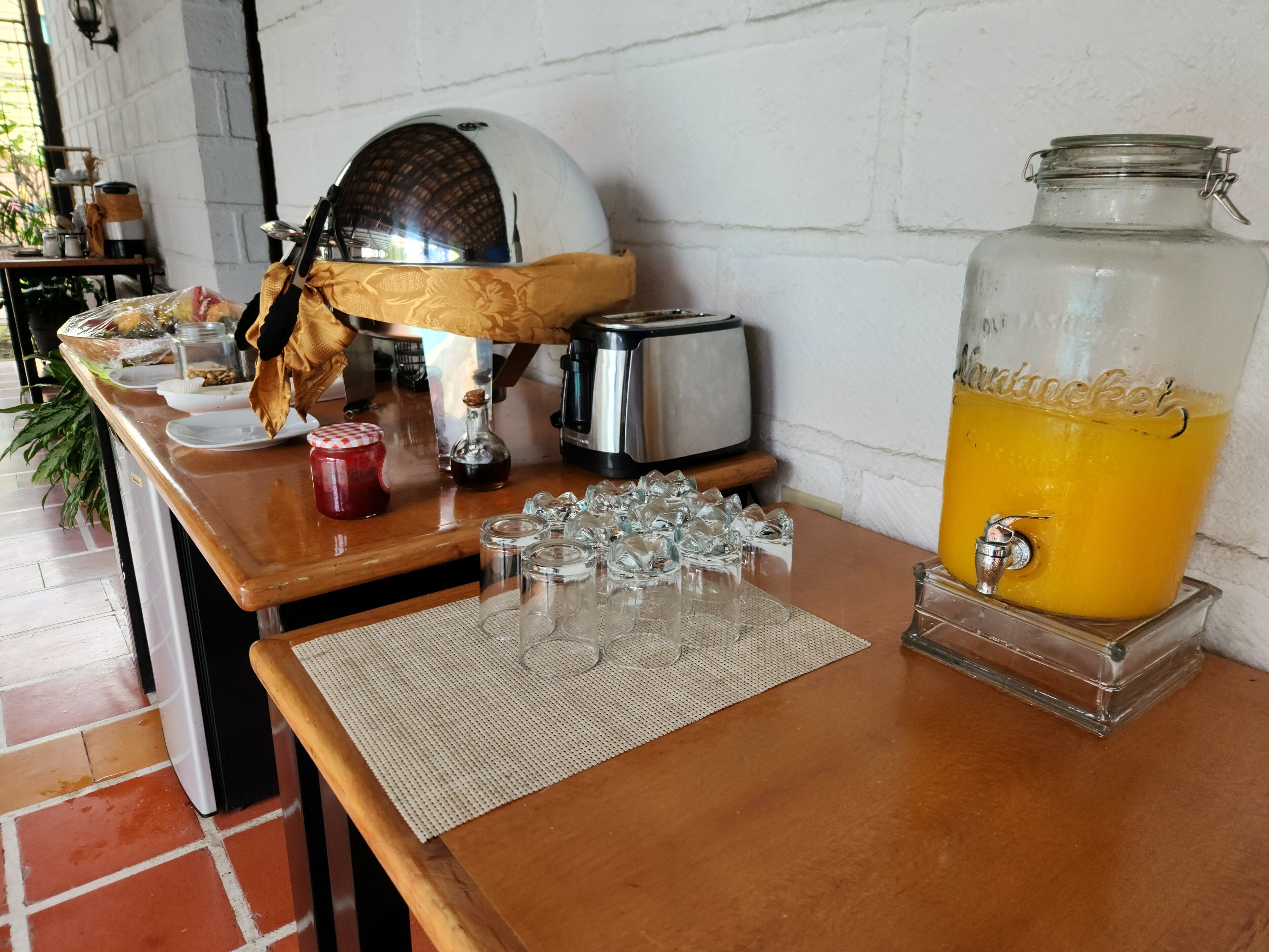 A breakfast bar with a coffee maker, toaster, and a large glass jar of orange juice.