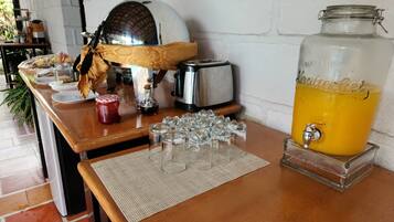 A breakfast bar with a coffee maker, toaster, and a large glass jar of orange juice.