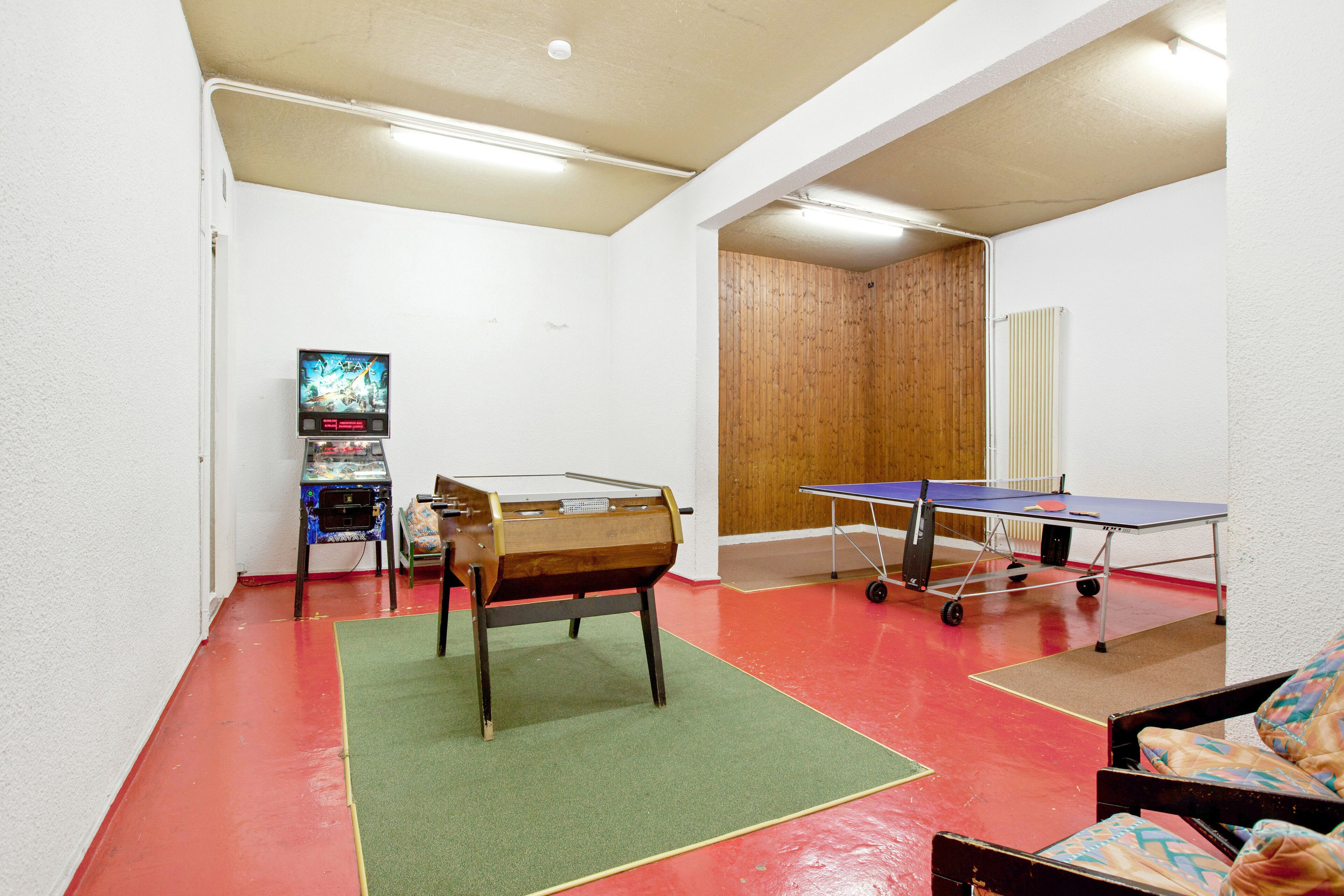 Ein Zimmer mit Tischtennisplatte, einer Couch und einem Fernseher.