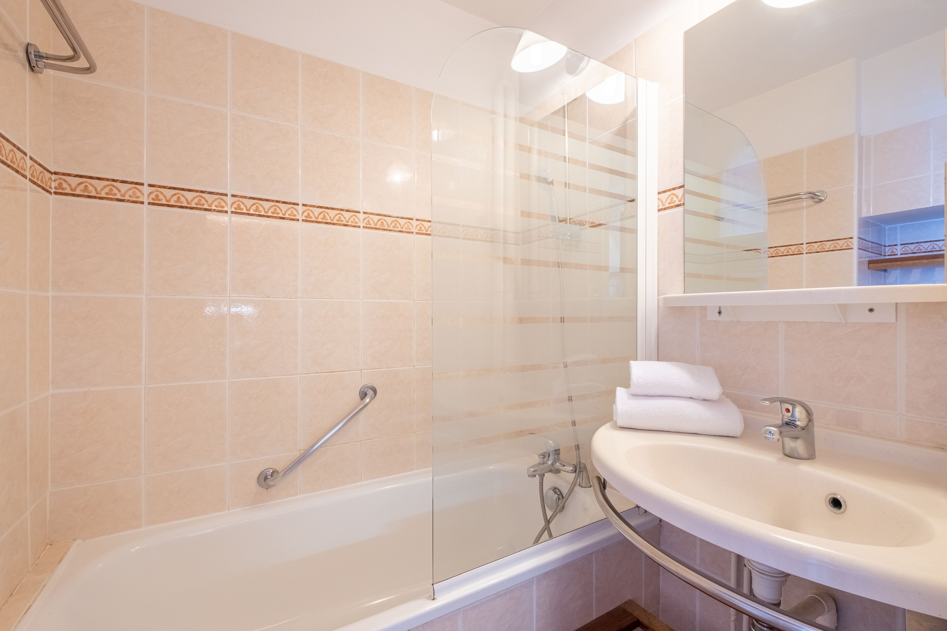 A bathroom with a bathtub, a glass-enclosed shower, and a sink with a mirror above it.