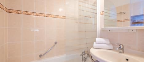 A bathroom with a bathtub, a glass-enclosed shower, and a sink with a mirror above it.