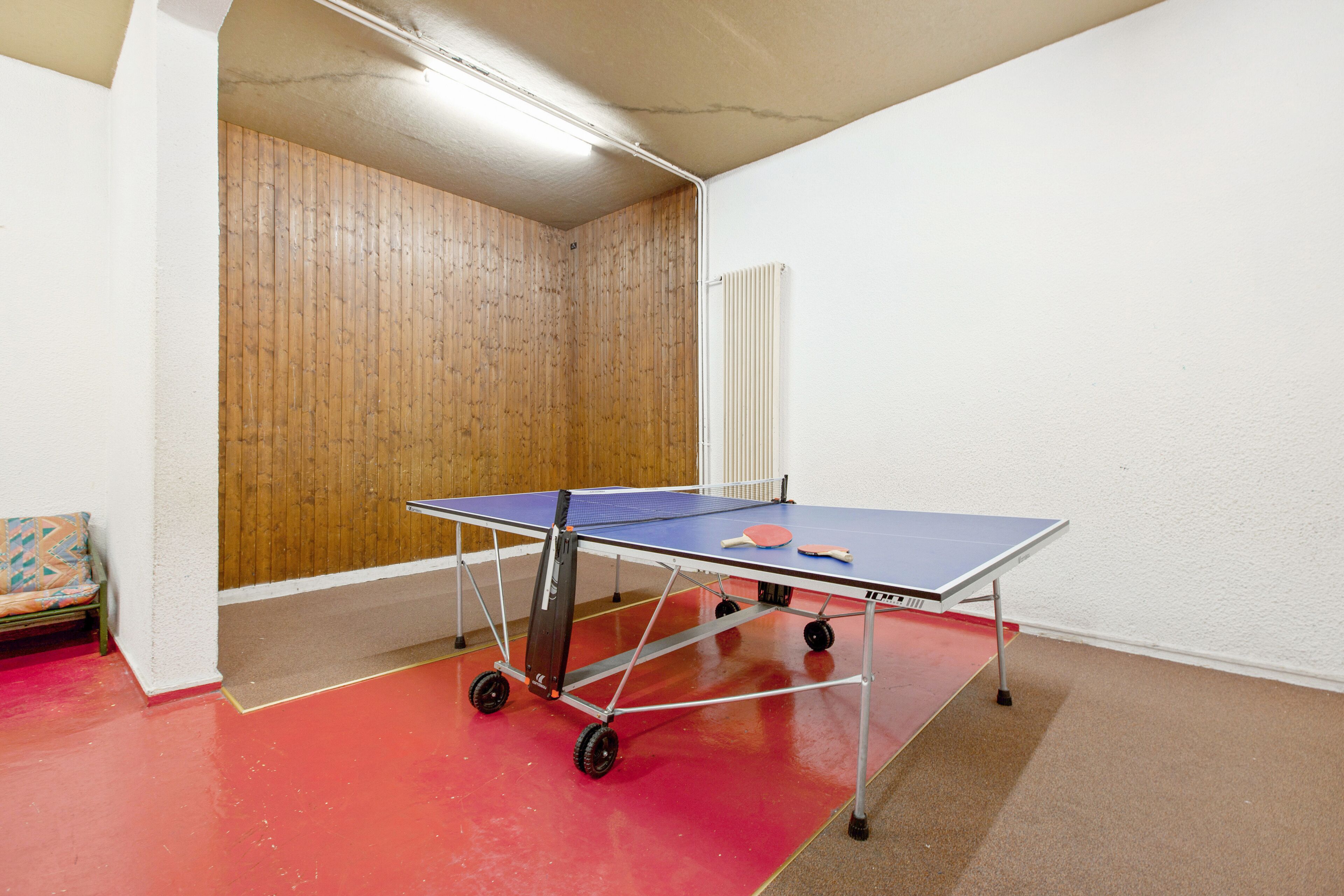 Une table de ping-pong dans une pièce avec un mur en bois et un radiateur.