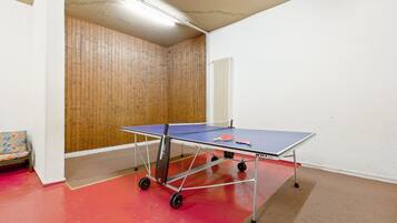 Une table de ping-pong dans une pièce avec un mur en bois et un radiateur.