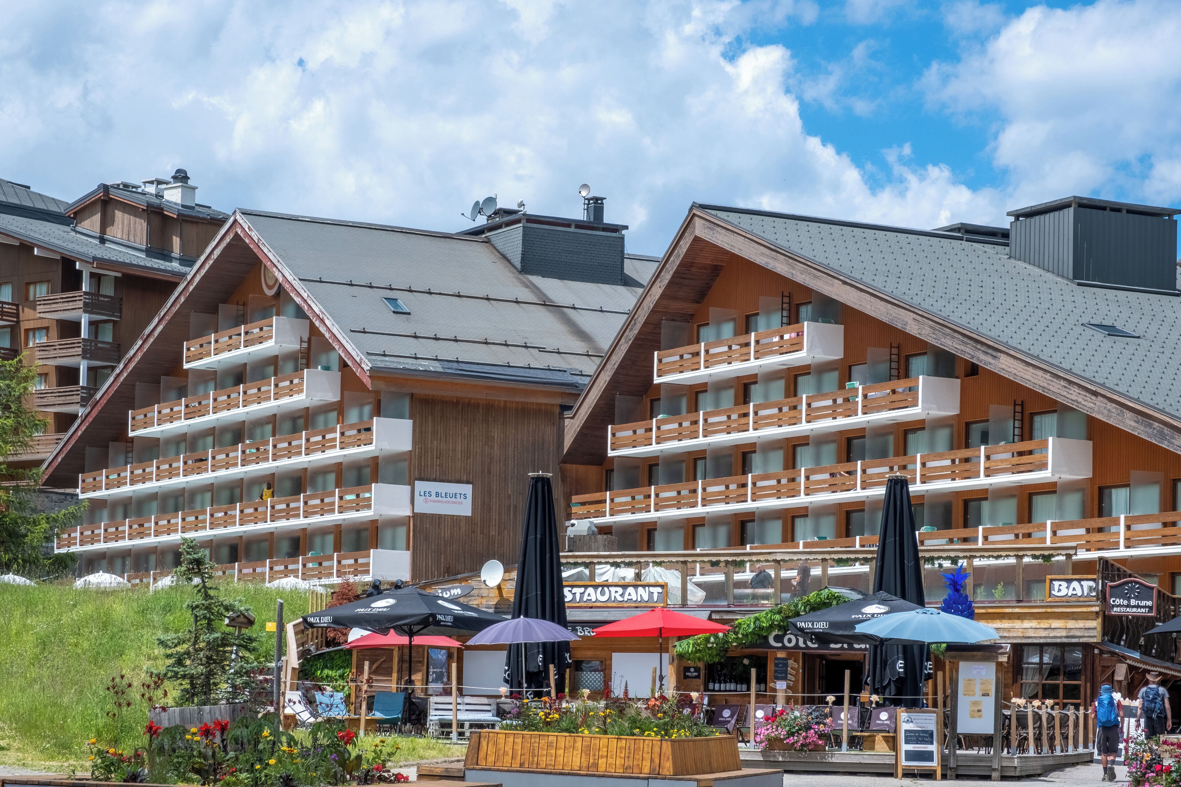 Ein Hotel mit mehreren Balkonen, Essbereichen im Freien und einem Schild, das ein Restaurant anzeigt.
