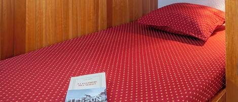 A bunk bed with a red polka dot bedspread and a book titled "La Pâtisserie des Enfites" on the lower bunk.