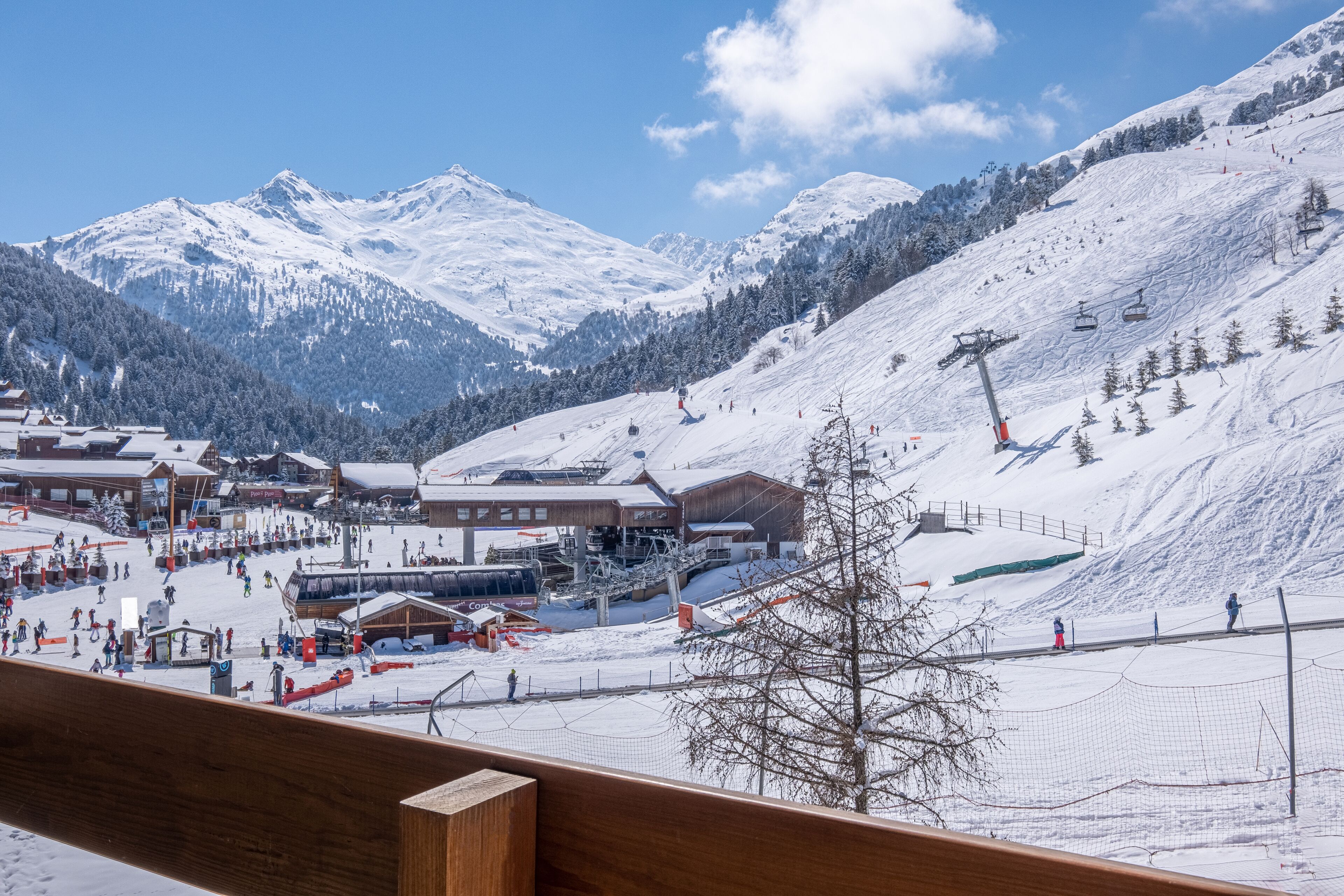 A snow-covered ski resort with buildings, a ski lift, and a mountain backdrop.