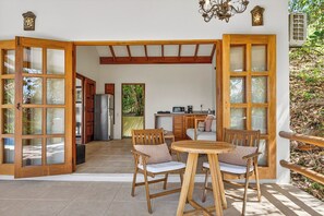 An open-plan living area with a kitchen, wooden furniture, and large windows. - Ocio Villas Mal Pais (Cóbano)