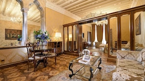 Une chambre luxueuse, ornée de lustres somptueux, d’un grand miroir et de meubles classiques.