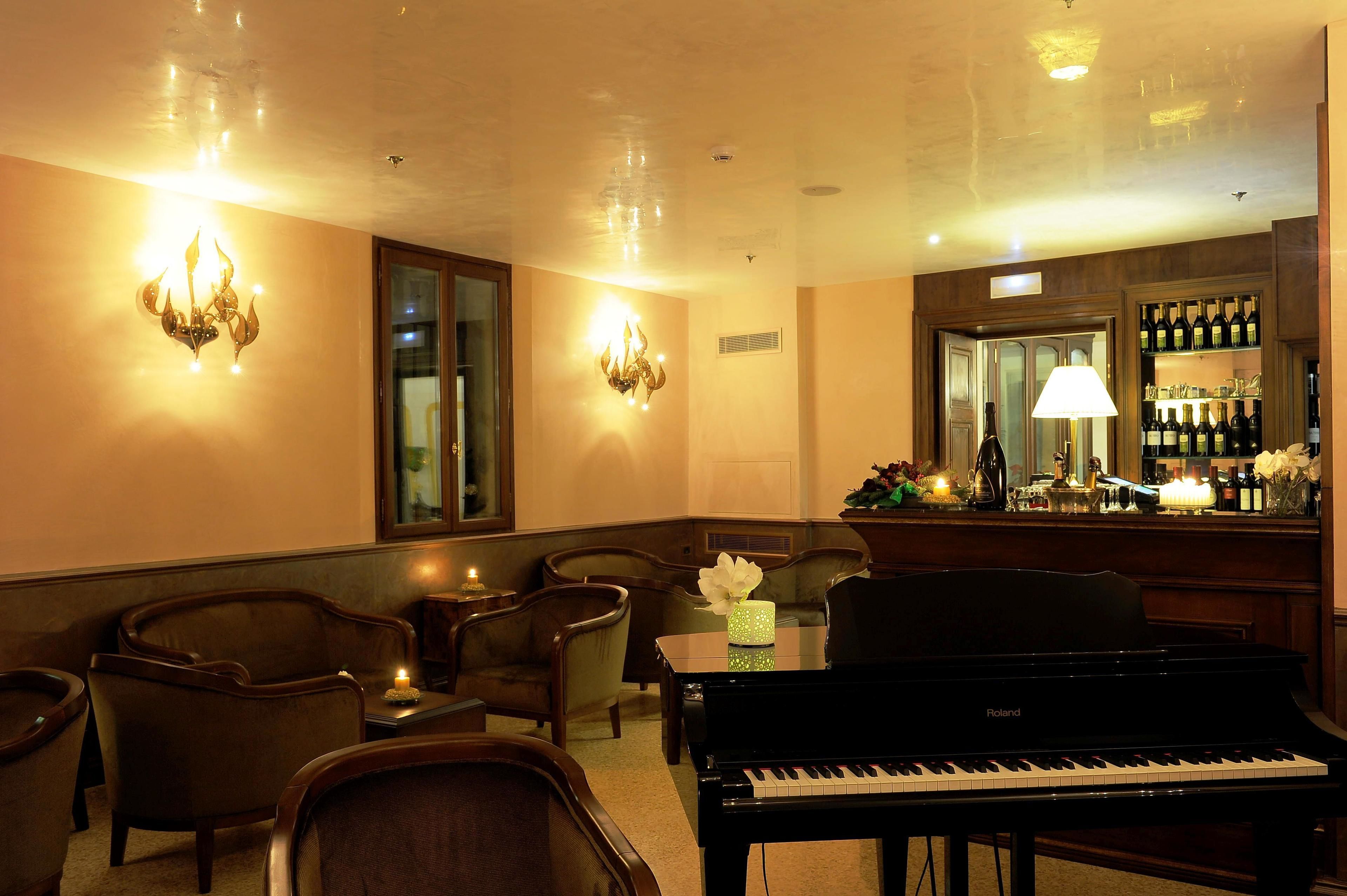 Una habitación con piano de cola, zona de estar y bar con botellas.
