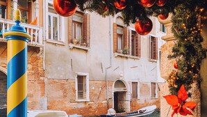 Une scène de canal avec des bateaux, un poteau rayé et un bâtiment doté d’un balcon.