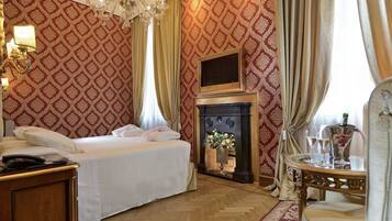Ein Hotelzimmer mit Bett, Kamin, einem Tisch mit Gläsern und einer Chandelier.