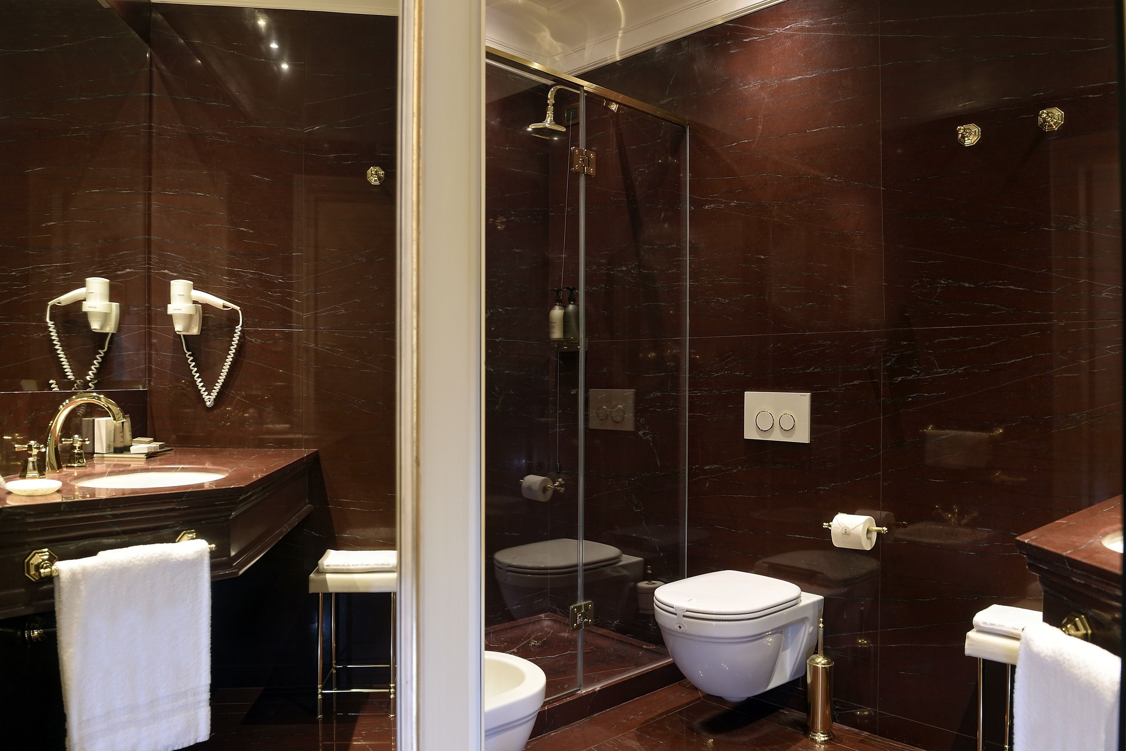 Un baño moderno con ducha de vidrio, lavamanos de mármol y un inodoro.