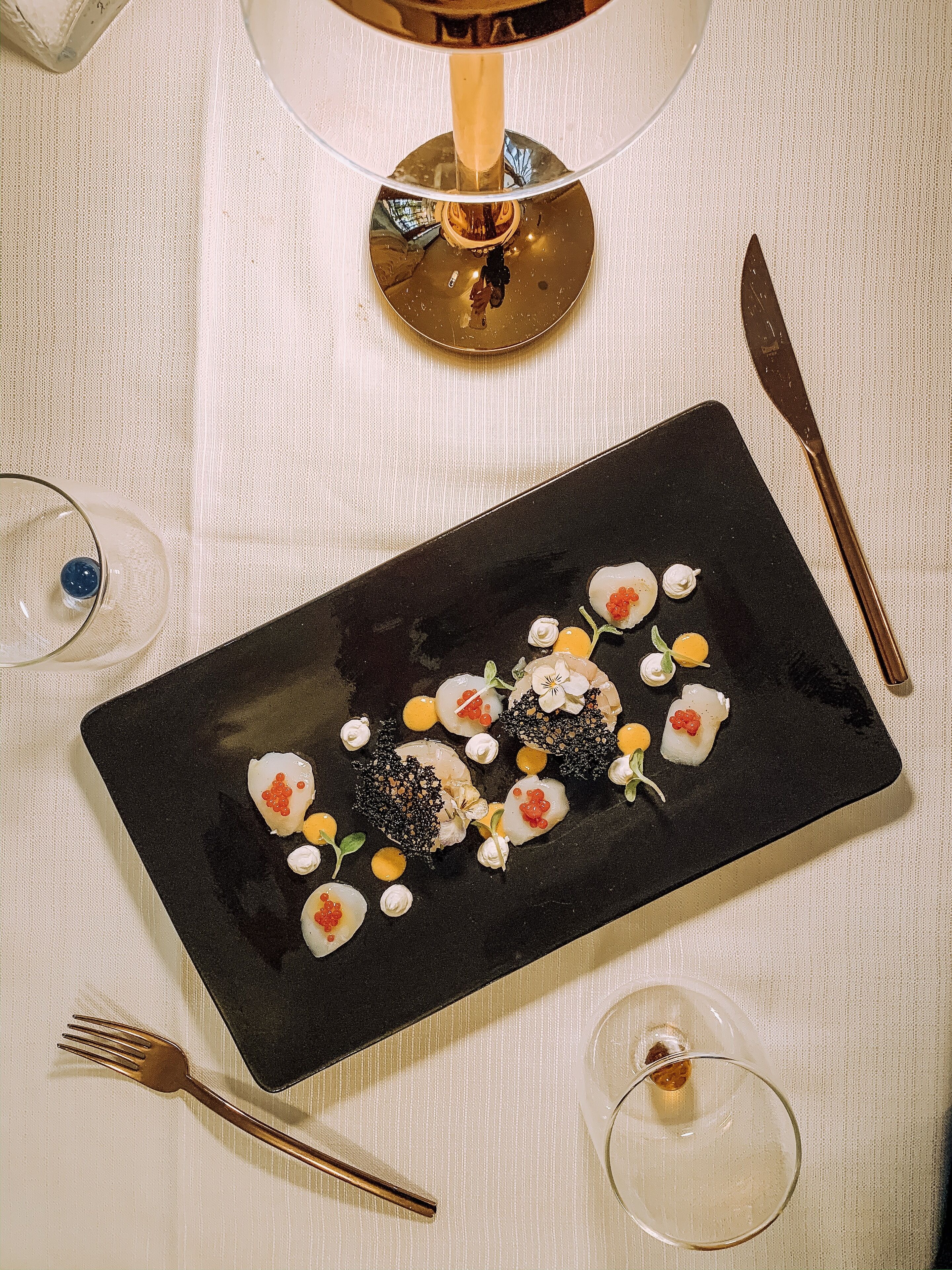 Un plato rectangular negro con sushi sobre un mantel blanco con textura.