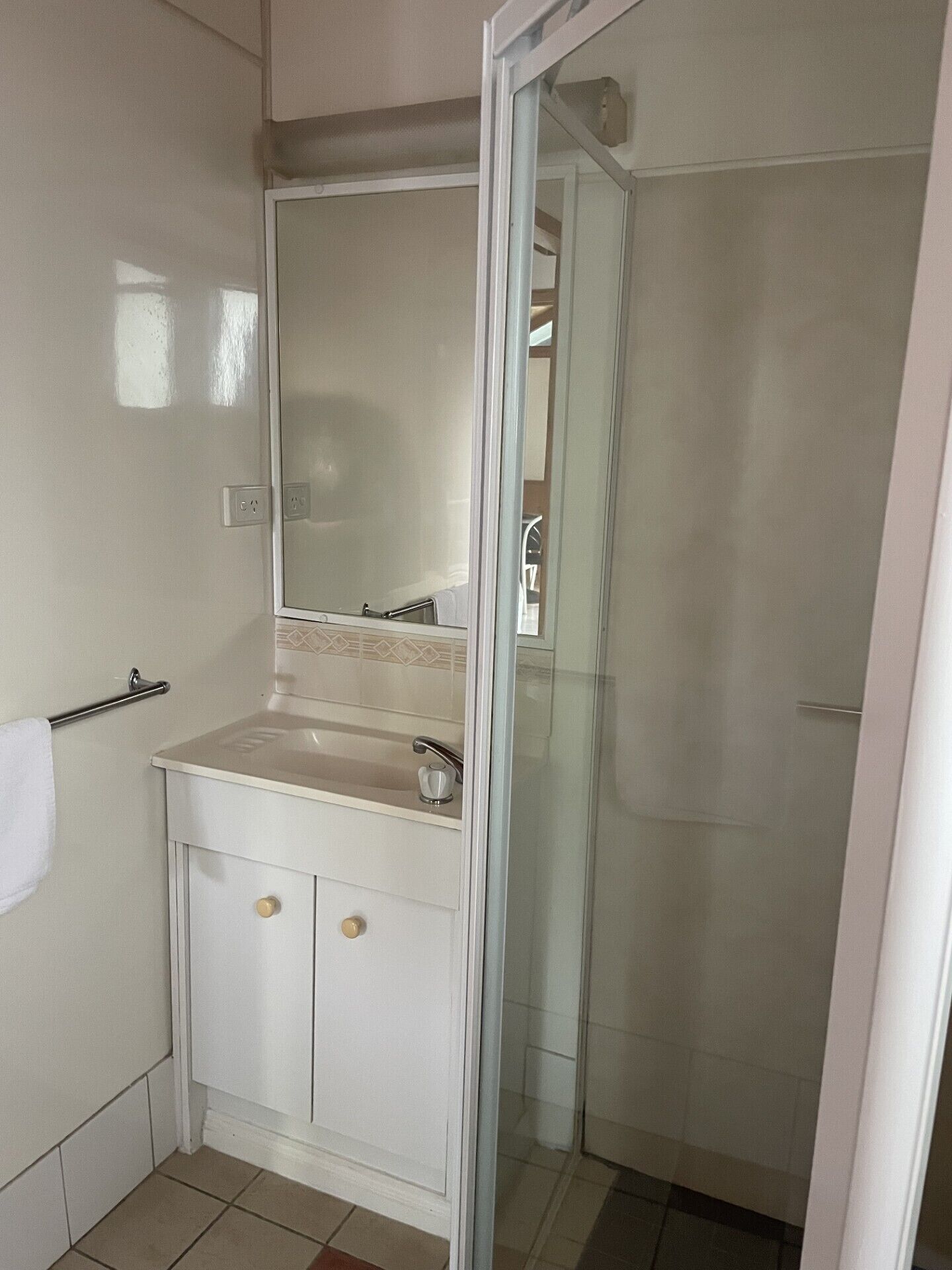 A bathroom with a sink, mirror, and shower.