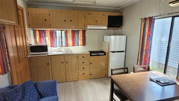 A compact kitchen with wooden cabinets, a microwave, a refrigerator, and a dining area with a table and chairs.