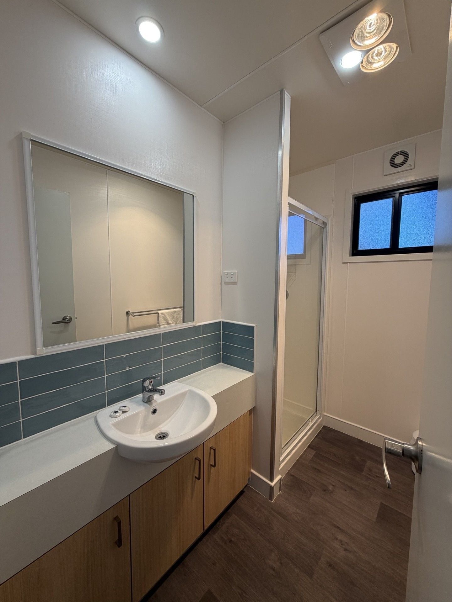 A bathroom with a sink, mirror, and shower.