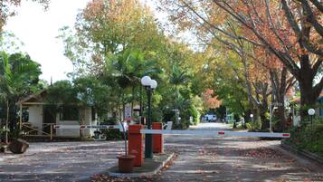 A gated entrance with a no tailgating sign, a small building, and trees with autumn leaves.