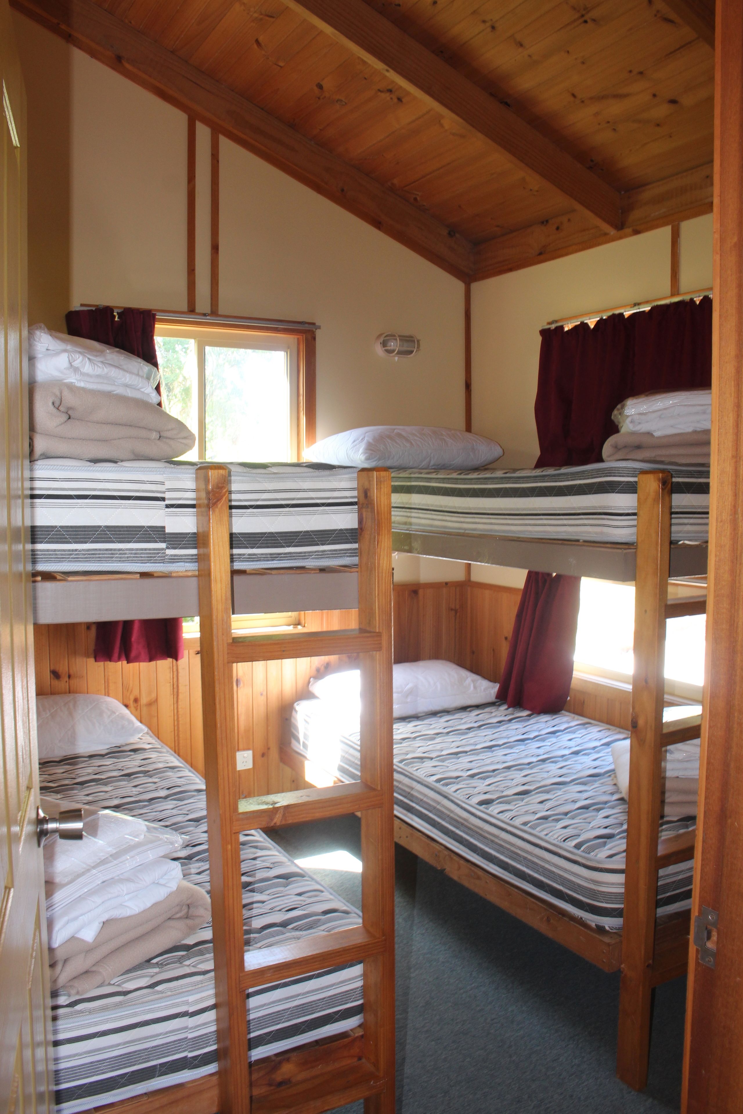 Camera con letto a castello, travi in legno e finestra con tende.
