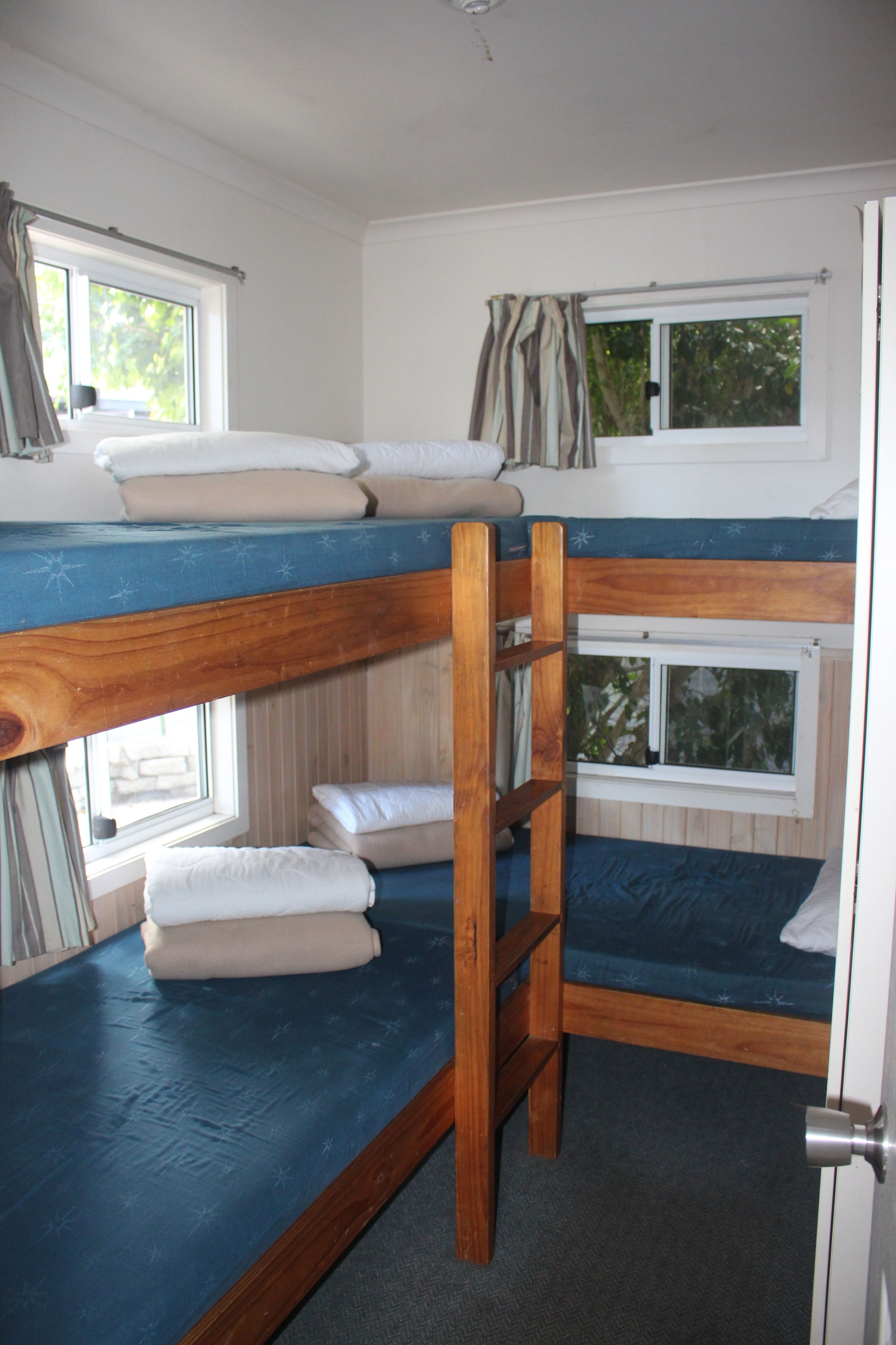 A bunk bed room with a window, curtains, and a door.